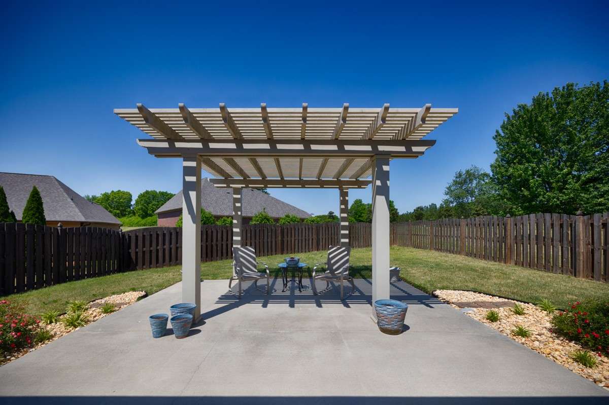 Back of house- Beautifully landscaped back yard with privacy fence, open patio with pergola, covered back porch with ceiling fan
