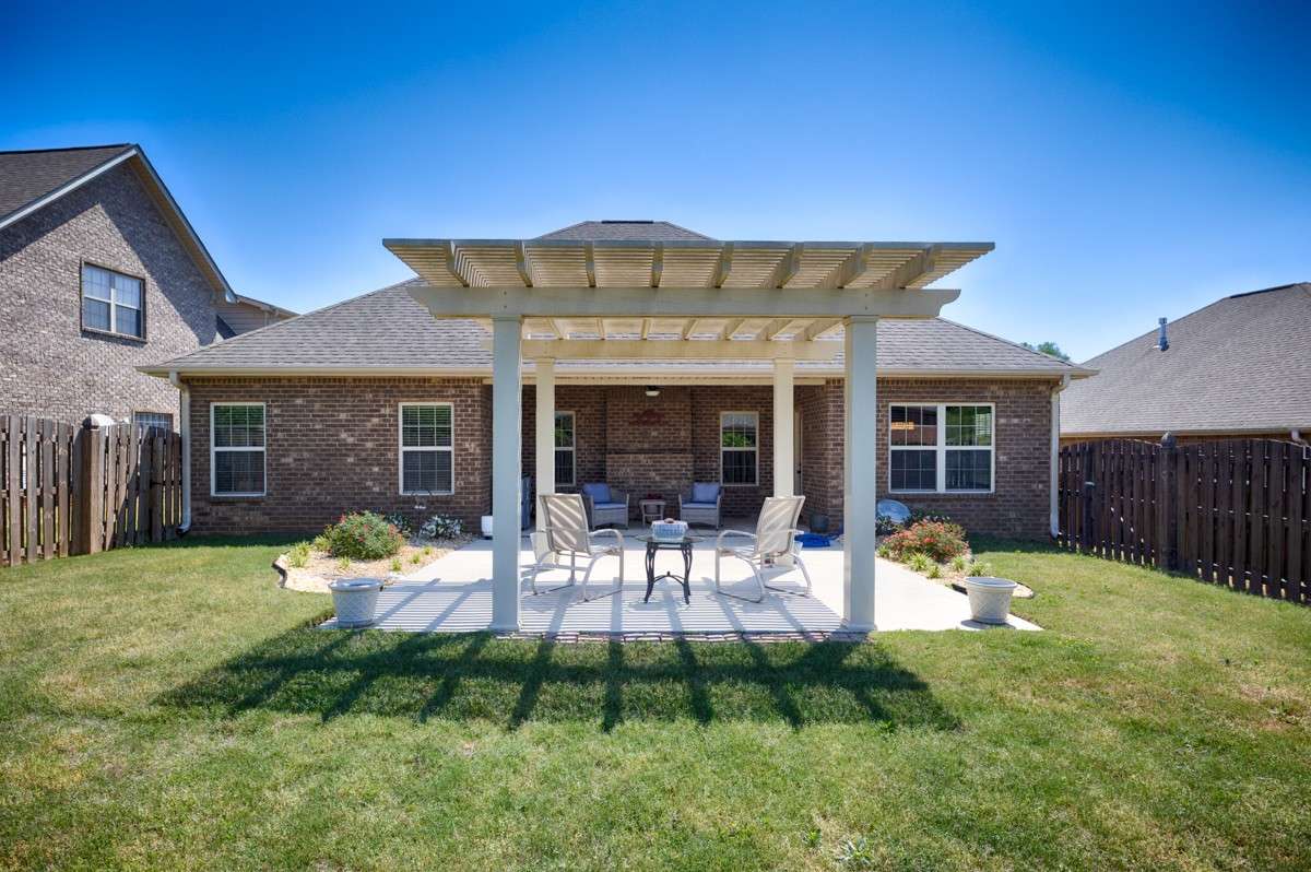 Back of house- Beautifully landscaped back yard with privacy fence, open patio with pergola, covered back porch with ceiling fan