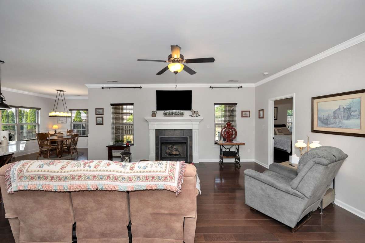 Living Room- wood flooring, crown molding, ceiling fan, fireplace
