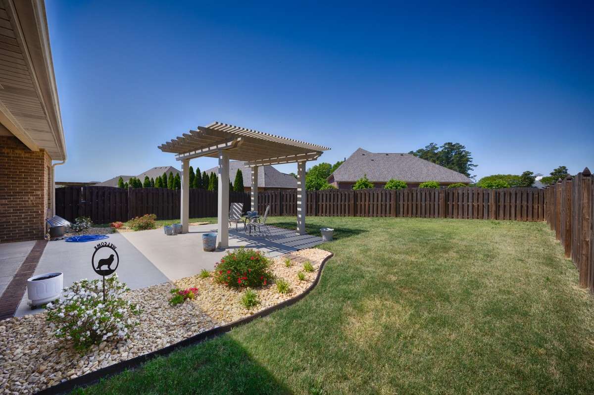 Back of house - Beautifully landscaped back yard with privacy fence, open patio with pergola, covered back porch with ceiling fan