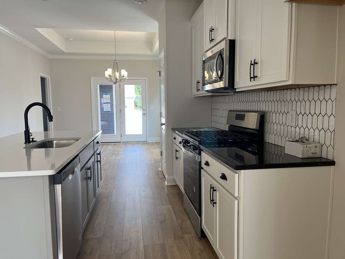 Kitchen with Island and lots of countertop space.  Includes tile back splash and laminate flooring.  SS appliances. NOT ACTUAL HOME