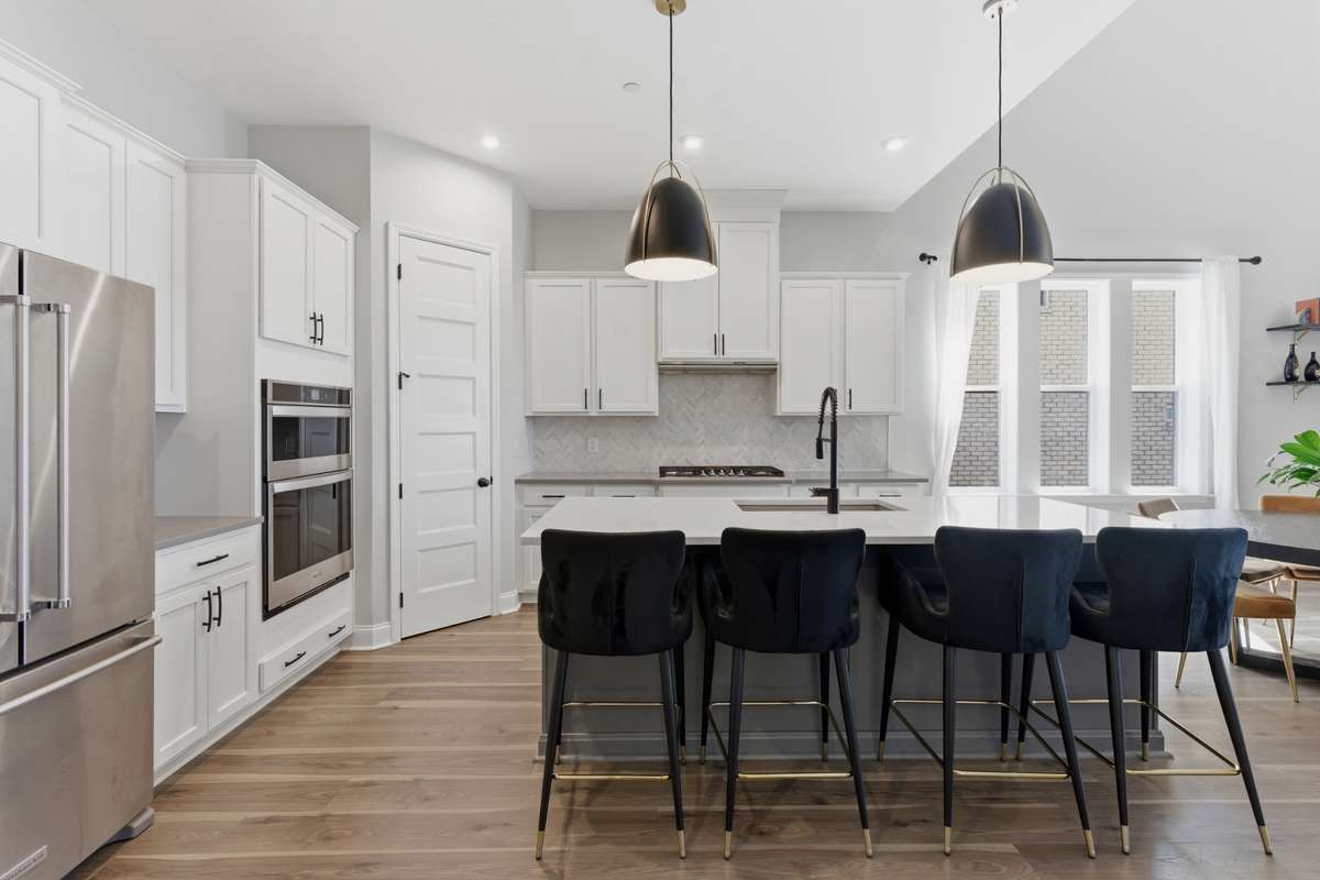 Enjoy your stainless steel appliances, including a gas range and double ovens, paired with a custom tile backsplash that adds subtle texture.