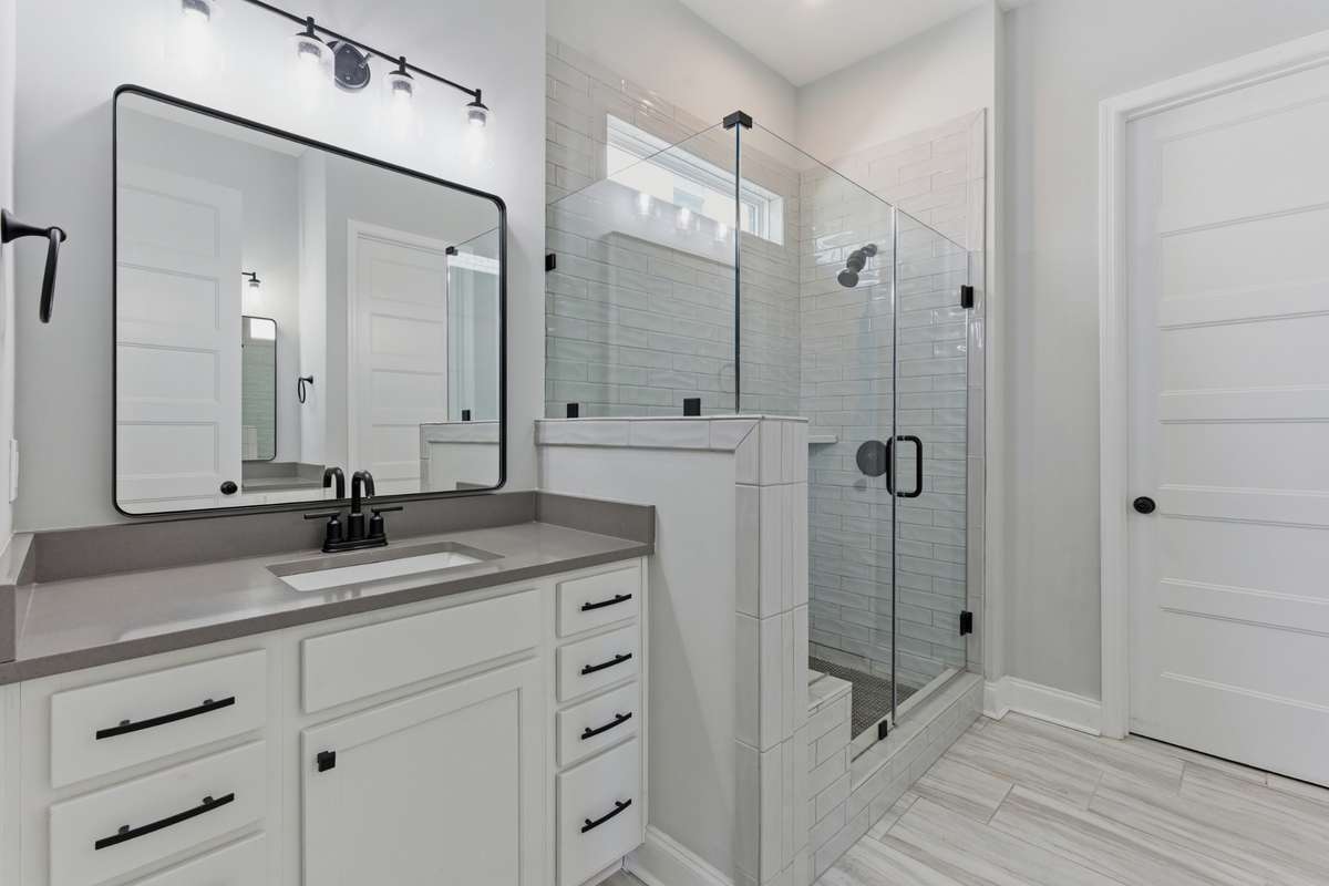 En suite bath features a walk-in shower with glass enclosure and clean, modern finishes.