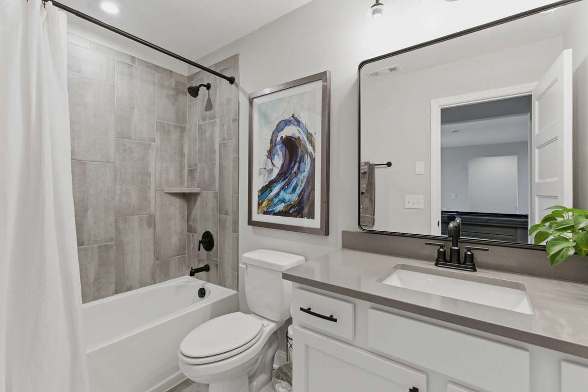 Full secondary bathroom conveniently located between the first two bedrooms, featuring a clean vanity and ample counter space for everyday use.