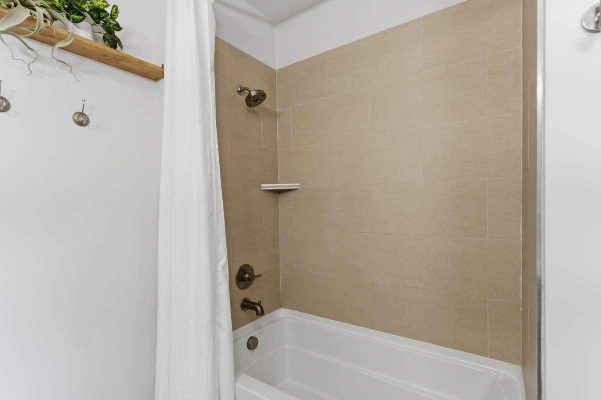 A tan tile surround frames the bathtub.