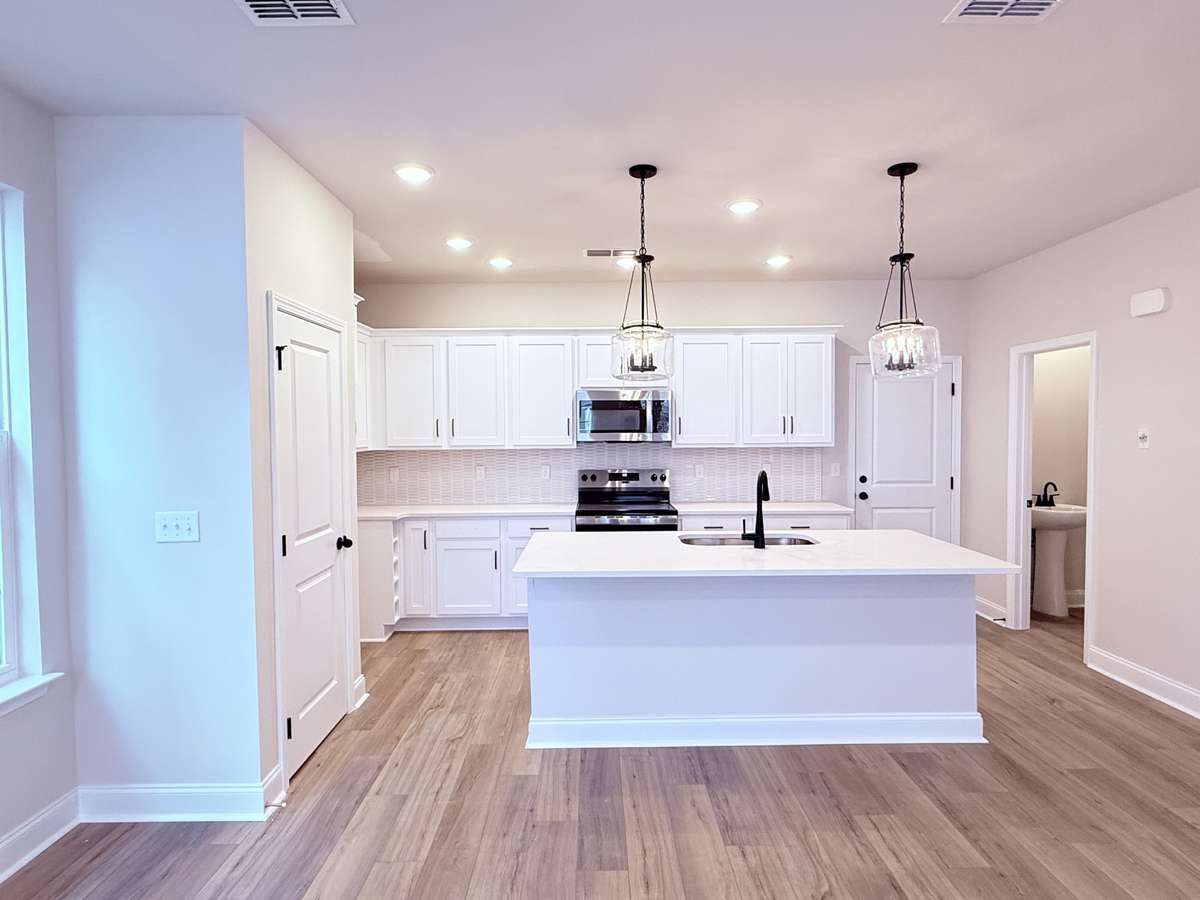 Black hardware, pendant lighting, and stainless-steel appliances perfectly accentuate the modern kitchen design.