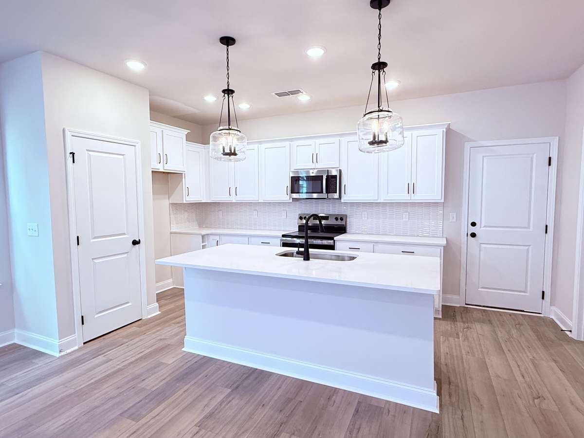 The kitchen features sleek white cabinetry with soft-close doors, quartz countertops, and a stylish mosaic tile backsplash.