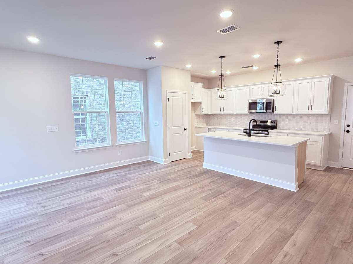 The dining area is perfectly positioned just off the kitchen, which also offers a generously sized island with seating. Durable LVP flooring flows throughout the main level, beautifully complemented by hardwood stairs leading to the second floor.