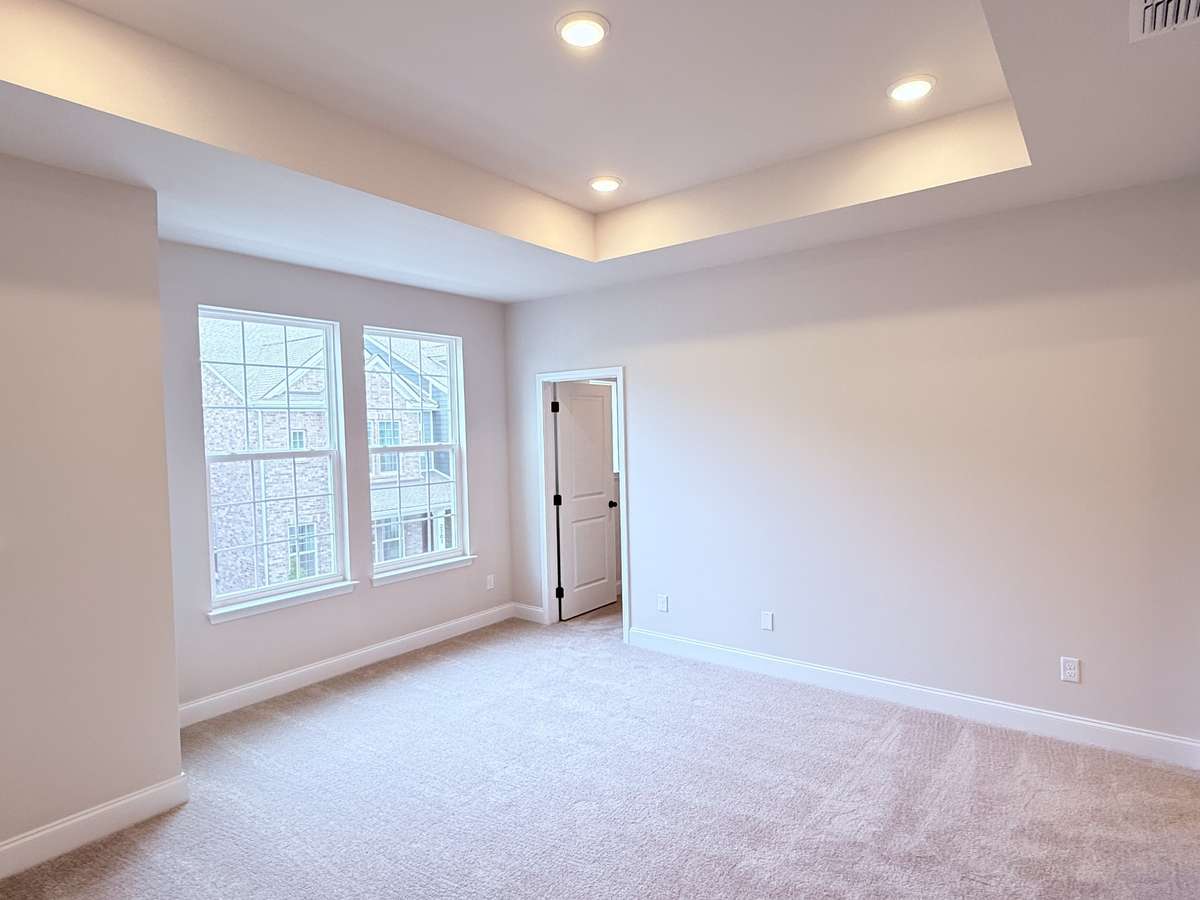 The spacious primary suite boasts a tray ceiling and tranquil views of the courtyard.