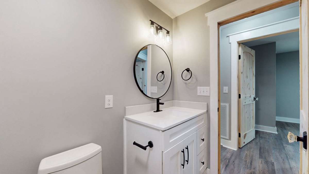 Another view of the second bathroom with upper end toilet, vanity, lighting, and mirror