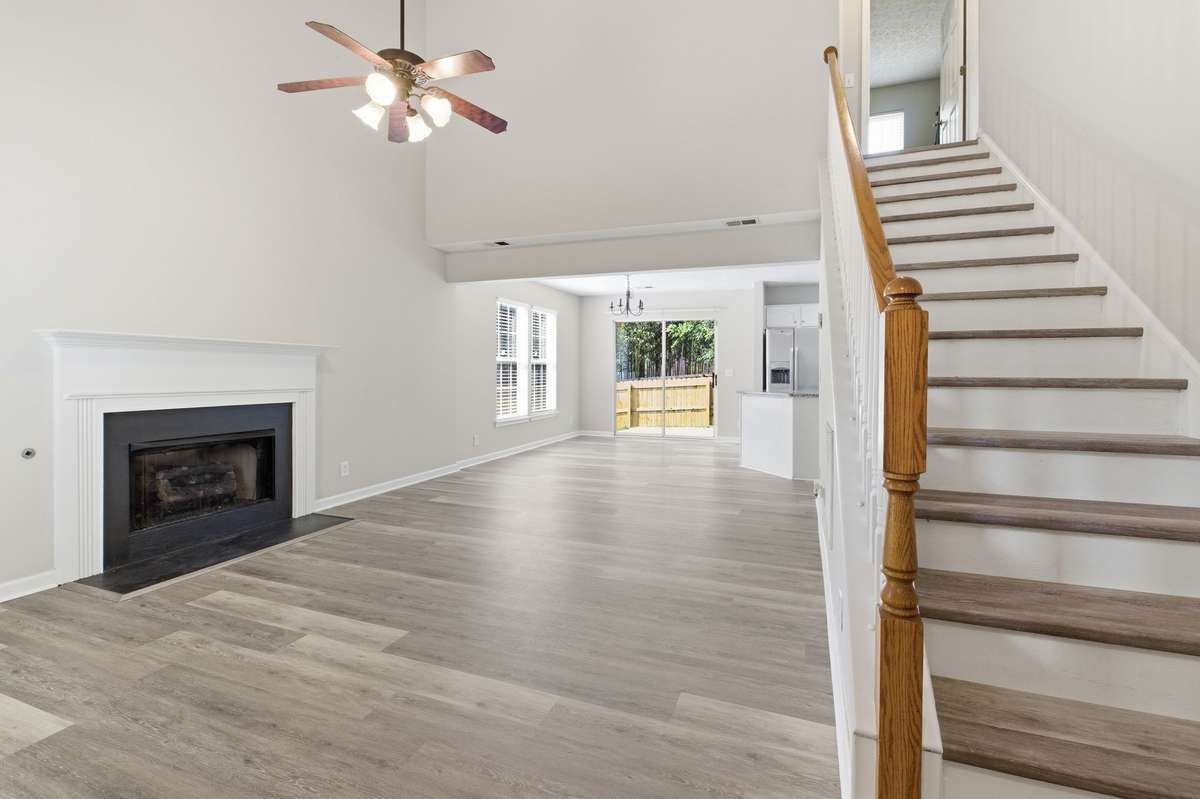 Stunning living room boasting soaring two-story vaulted ceilings, a ceiling fan, and open staircase
