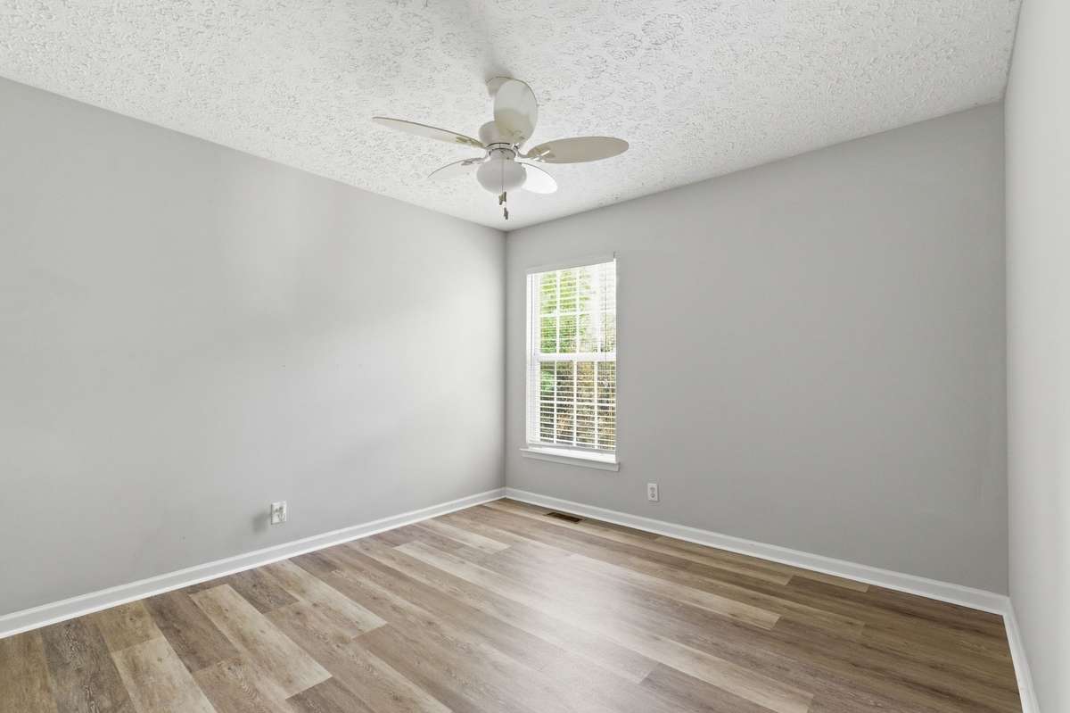 Generously sized secondary bedroom featuring a ceiling fan, large window, and new LVP flooring.
