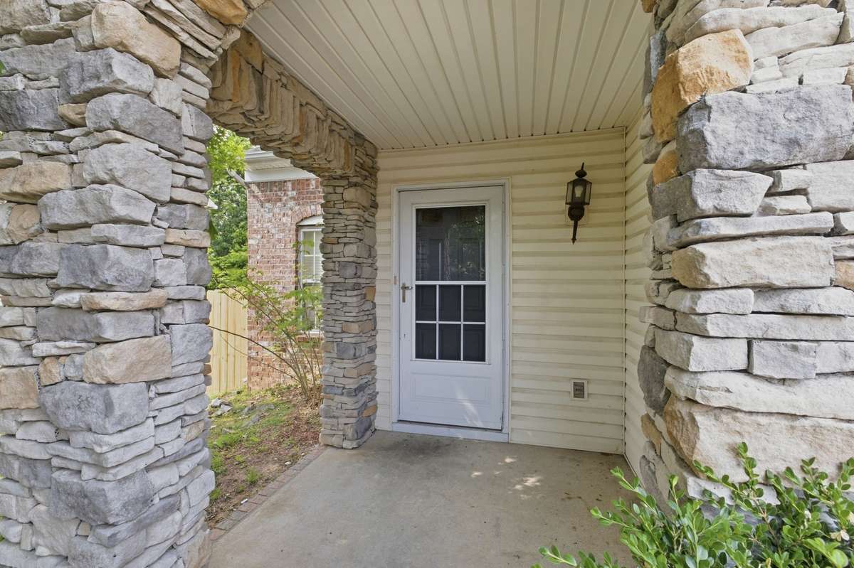 Charming covered front porch featuring custom stone column accents