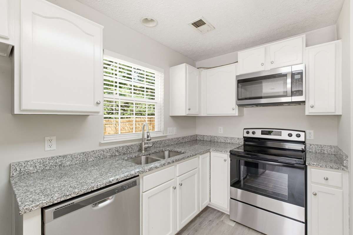 Well-appointed kitchen showcasing a brand new stove, stainless microwave, and dishwasher.