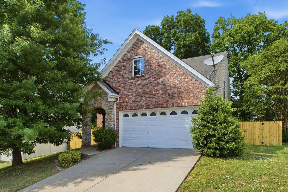 Front exterior featuring a charming brick and stone facade with a 2-car garage.