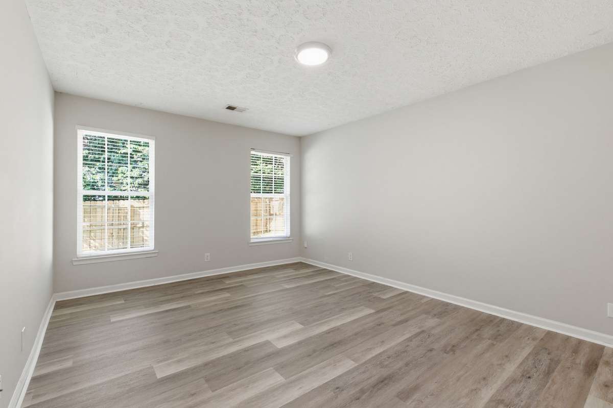 Spacious Main-Level Master Bedroom with brand new LVP flooring and fresh, neutral paint.