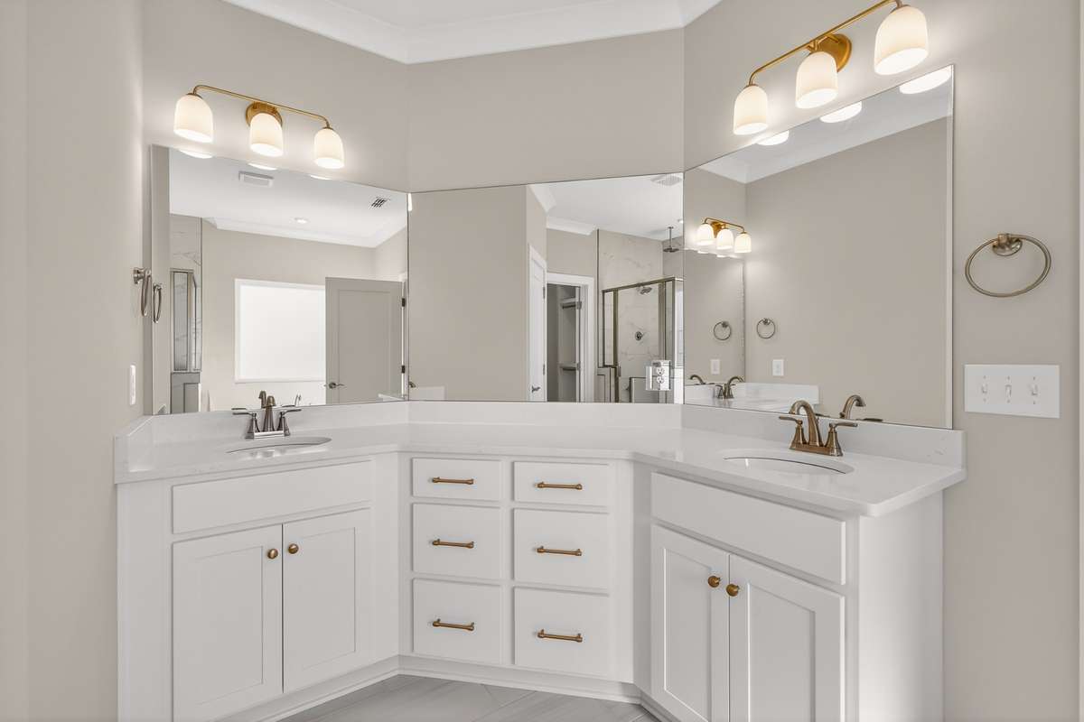 Primary bathroom with double vanities and tile shower with rain shower head
