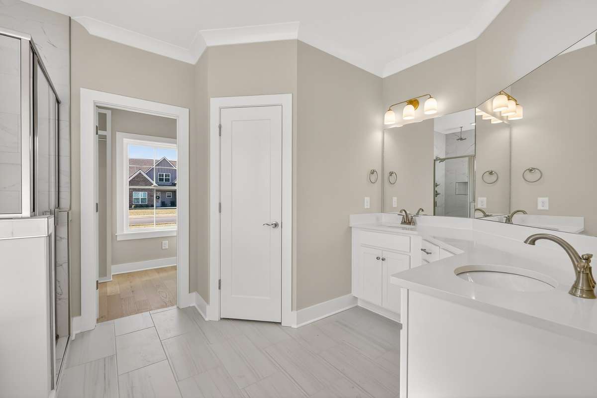 Primary bathroom with double vanities and tile shower with rain shower head