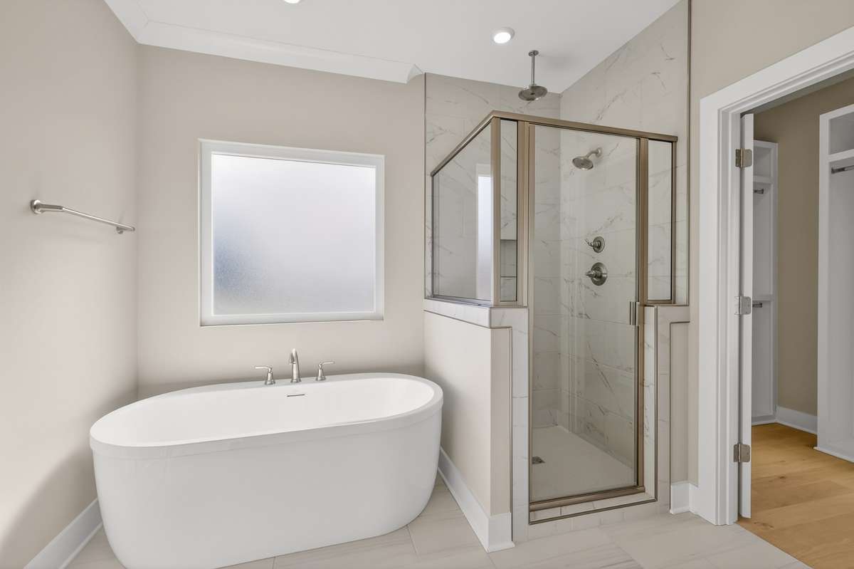 Primary bathroom with double vanities and tile shower with rain shower head