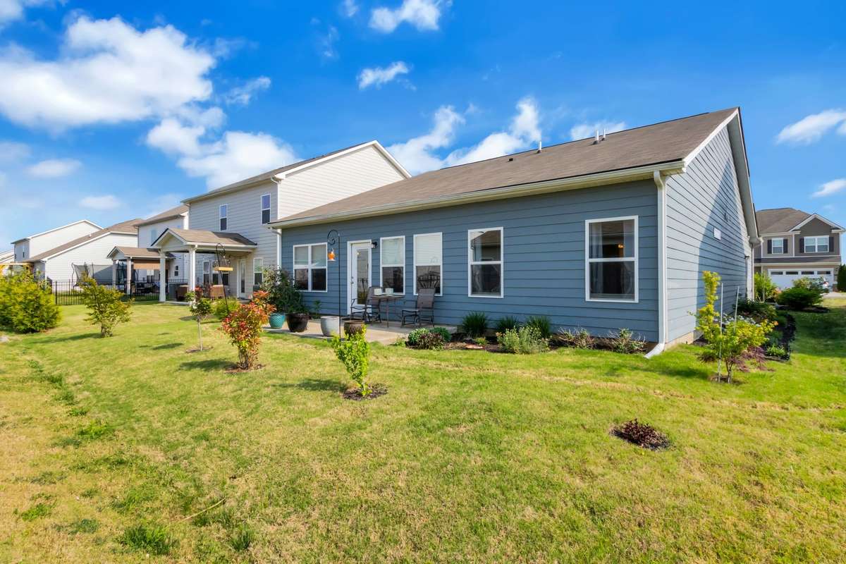 Beautifully landscaped backyard features a patio for outdoor dining, open green space, and a serene setting to enjoy morning coffee or evening sunsets.
