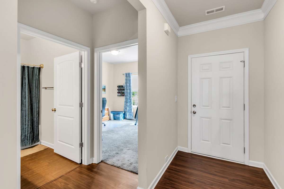 Inviting foyer entry showcases rich flooring, crown molding, and a functional split-bedroom layout with convenient access to guest bedroom and bath.