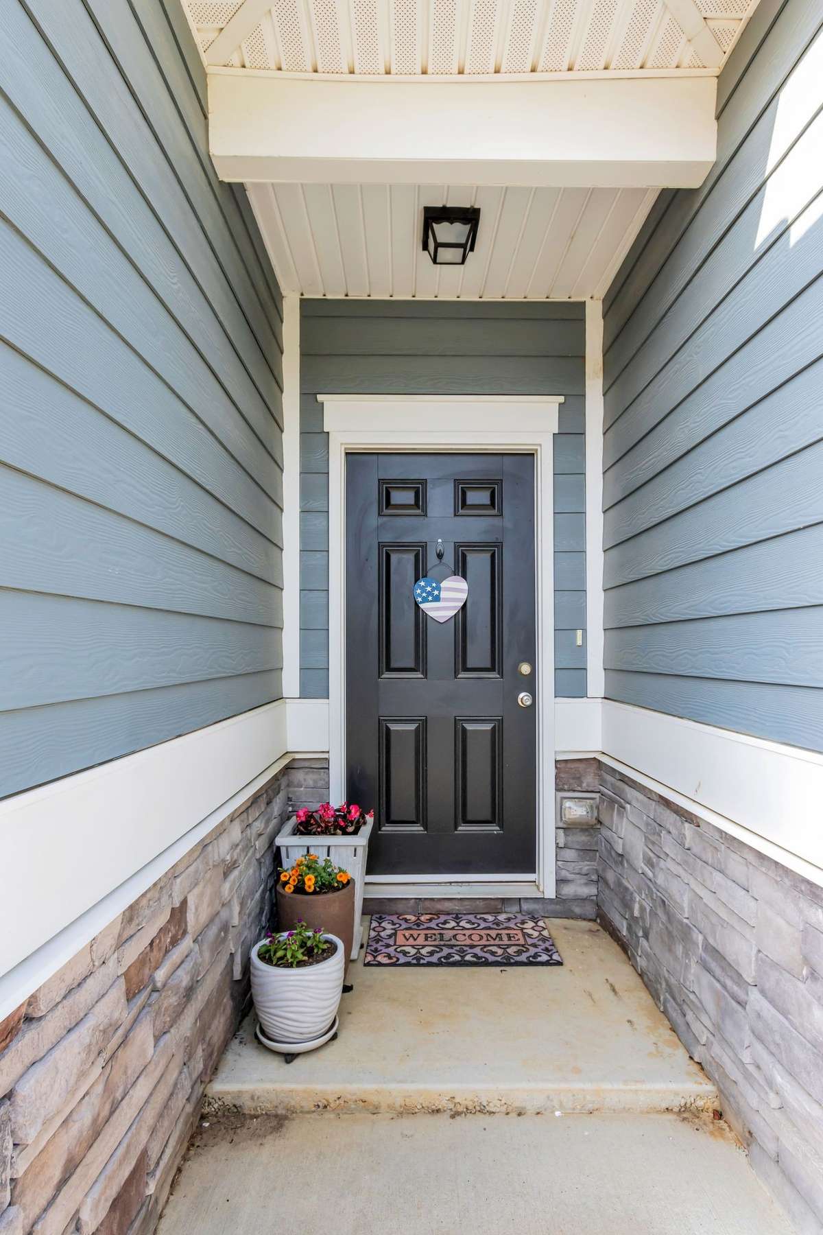 Inviting covered front porch with beautiful stone accents and charming architectural details offers a warm and welcoming first impression.