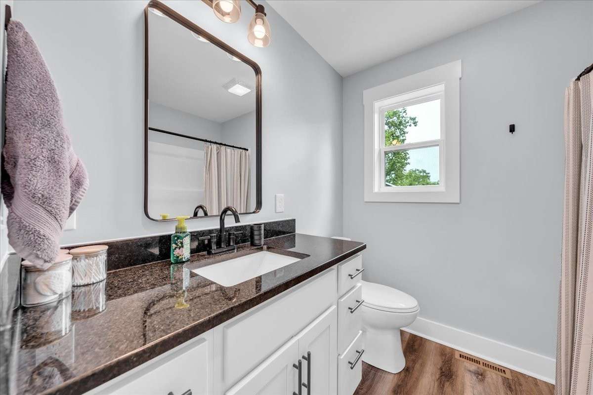 Guest bath with large single vanity with granite countertops, luxury vinyl flooring and shower/tub combo.