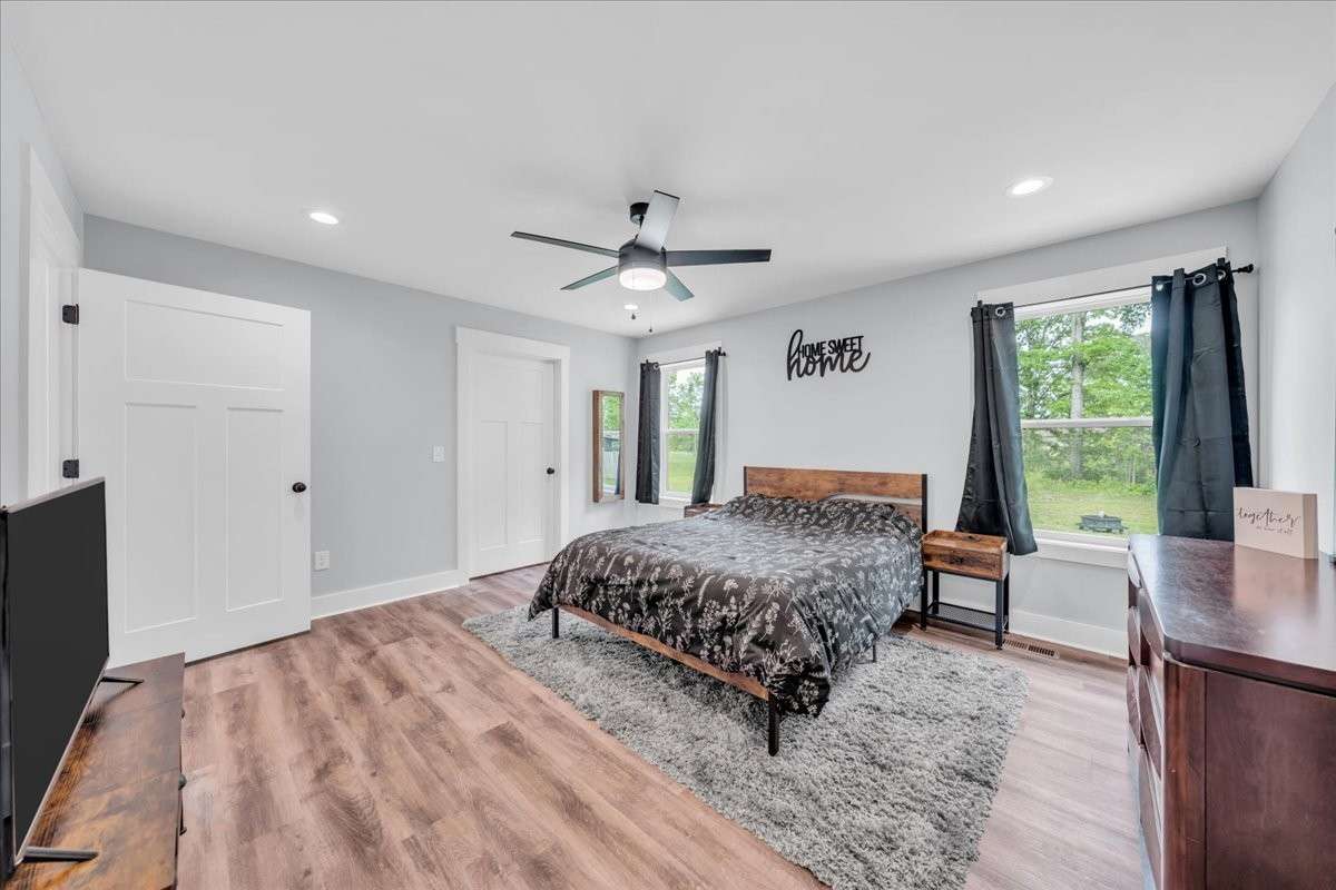 The primary bedroom is a true retreat with ceiling fan, recessed lighting, sunny windows and large walk-in closet.