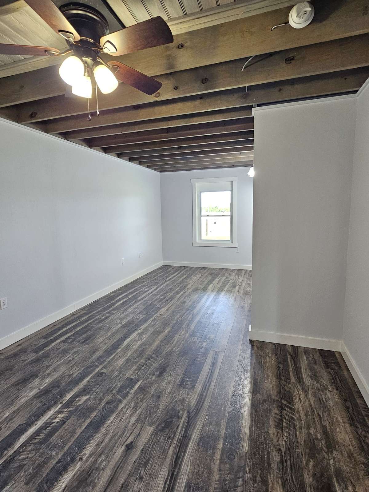 The bedroom in the home is large and has ceiling fan, room for a sitting area, a window to the rear of the property, and a large, well appointed walk-in closet.