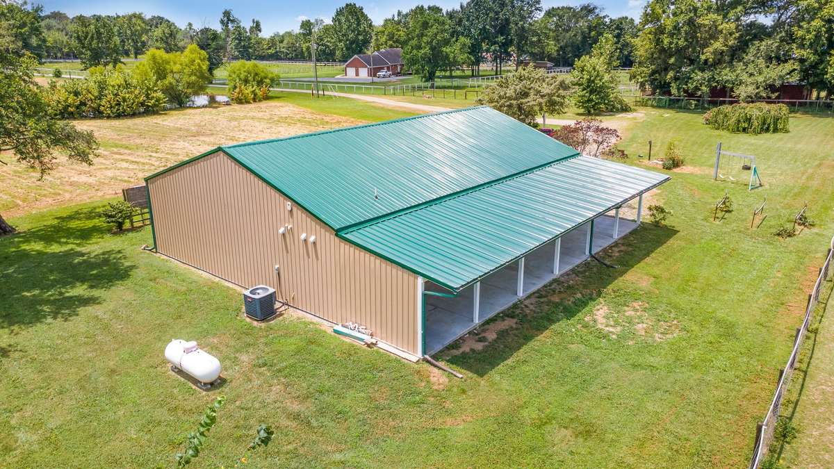 In this photo, we get a look at just how large the home is overall and we also see the blackberry bushes, grape vines, and peach trees off to the right. You can't get much more authentic Tennessee barndominium than this!