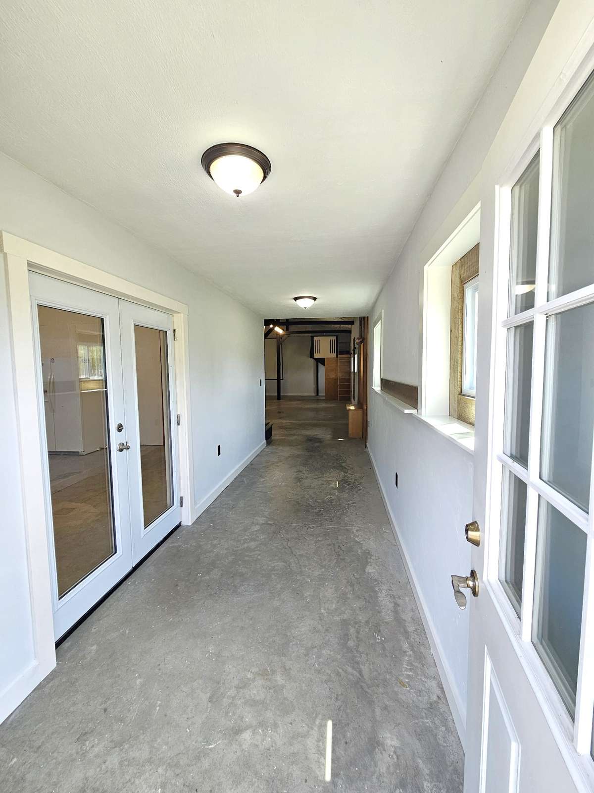 The entry foyer / hall is a great place for a side table or a bench.  Concrete flooring is durable and easy to clean should you accidentally bring muddy shoes / boots in! The fire rated french doors on the left lead to the garage / workshop.