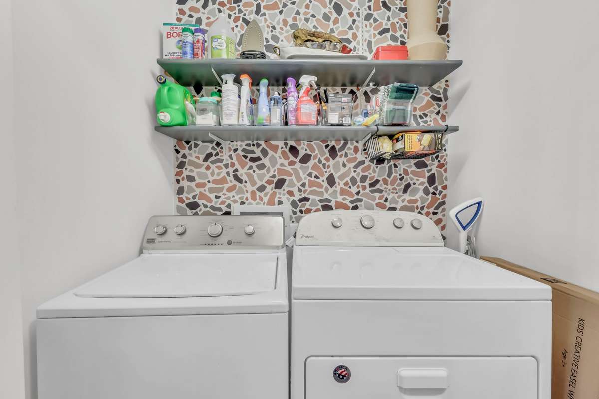 The laundry room features a trendy accent wall. Washer + dryer remain