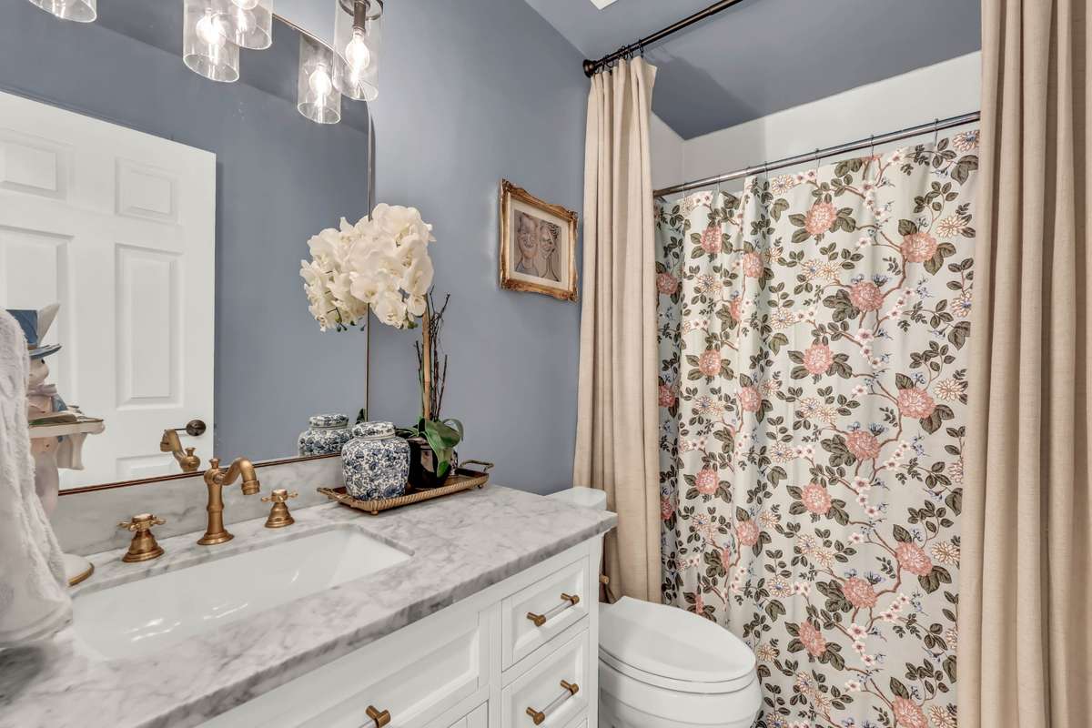 Completed remodeled guest bath with gold accents + tile flooring + stunning vanity + updated lighting + walk in shower