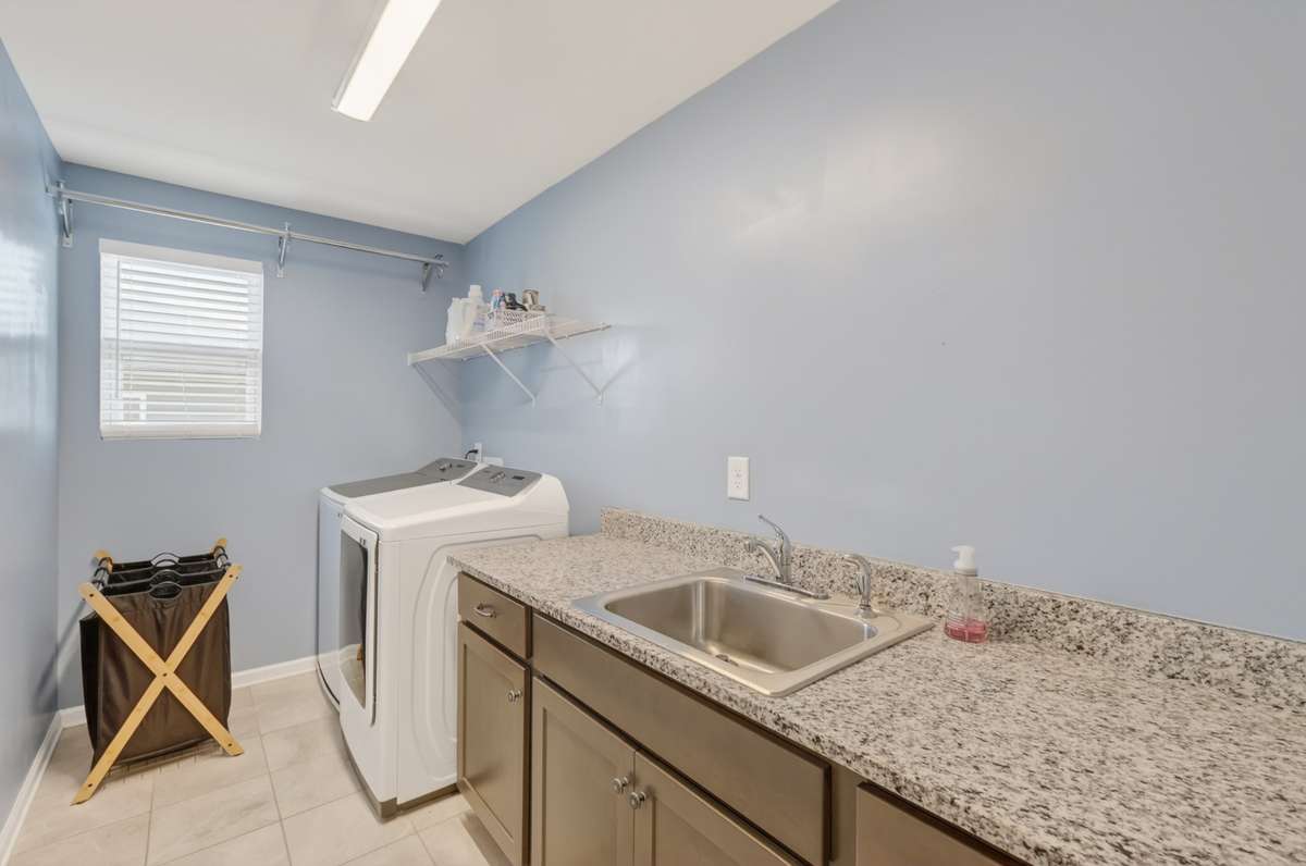 Utility Room with granite counter tops, wash sink, and extra storage space