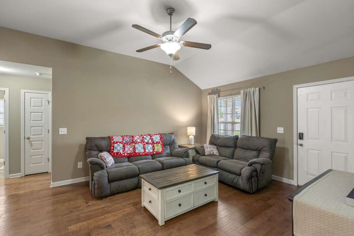 Warm and inviting living room featuring rich hardwood floors and soaring volume ceilings, creating a cozy yet open space perfect for relaxing or entertaining.
