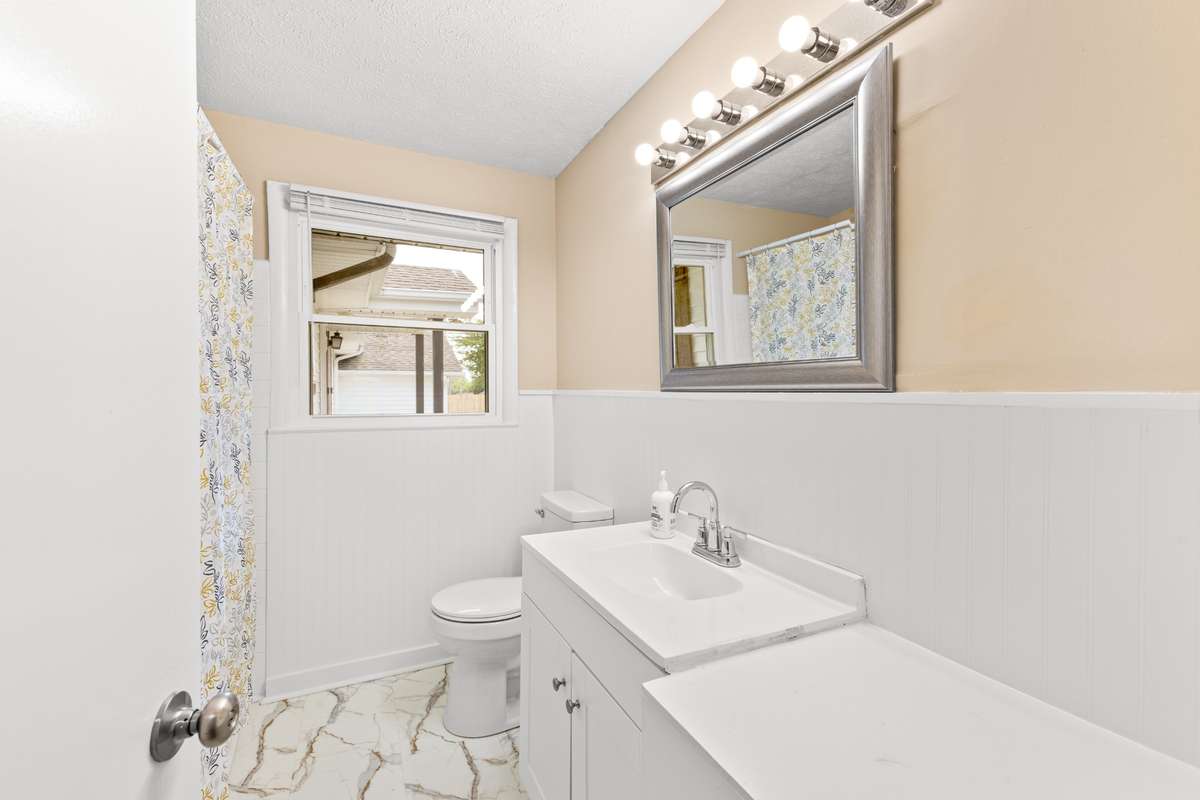 Full bath in the main part of the home with new flooring, painted bead board, new vanity and refreshed tub/tile surround.