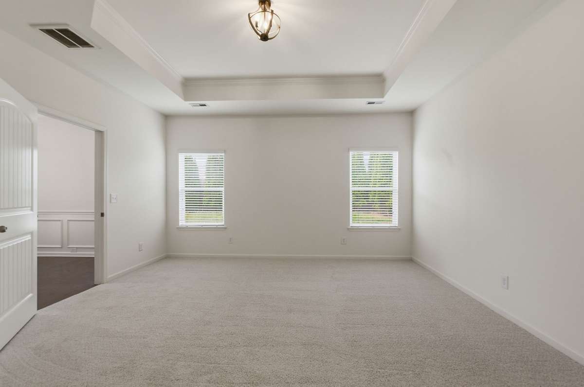 Spacious primary bedroom has tray ceiling and new carpet.
