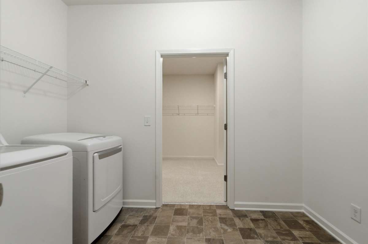 The large primary closet conveniently leads into the spacious laundry room. Washer and dryer remain.