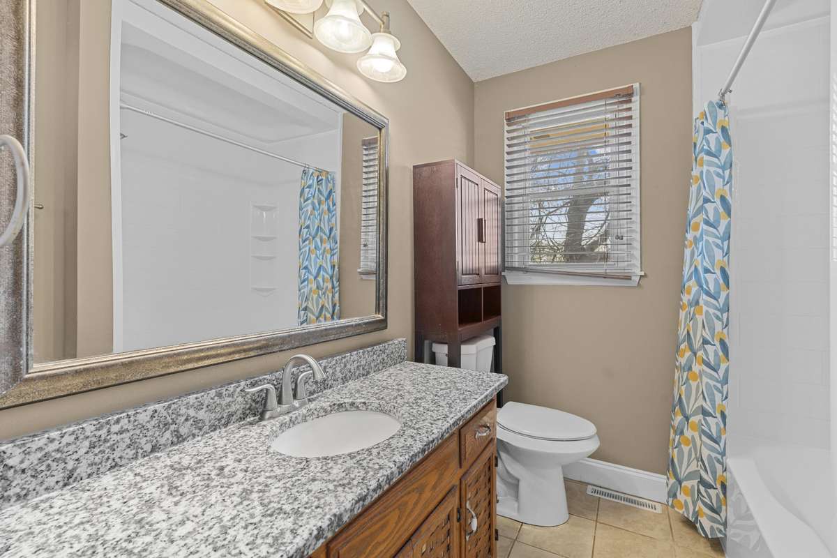 Full Bath With Granite Vanity And Tile Flooring