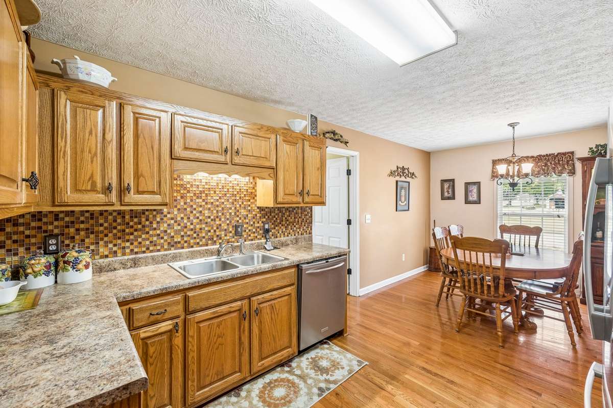 The Kitchen has oak cabinetry, backsplash, an eat-in area, and black/stainless appliances, all of which remain (Electric Stove, Microwave, Dishwasher & Refrigerator)!