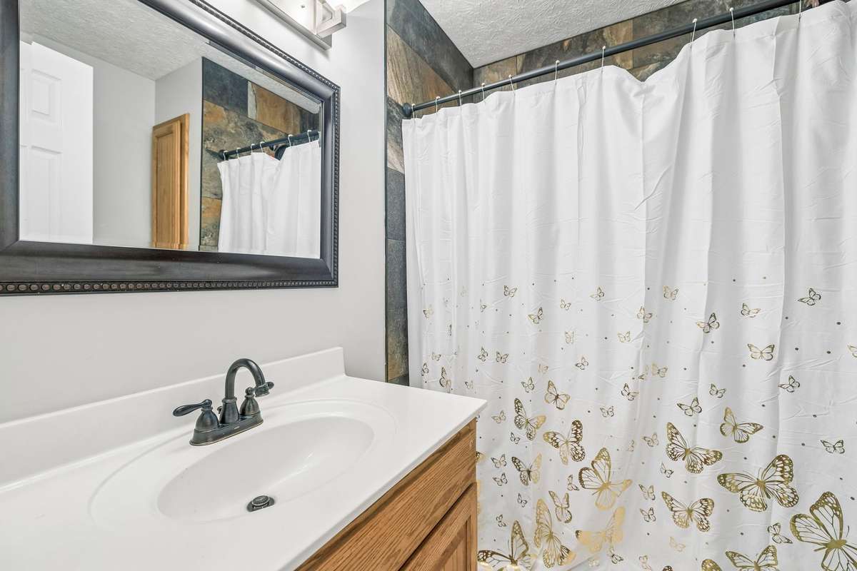 Bath 2 for the home has a walk-in tile Shower and vanity with a single sink.