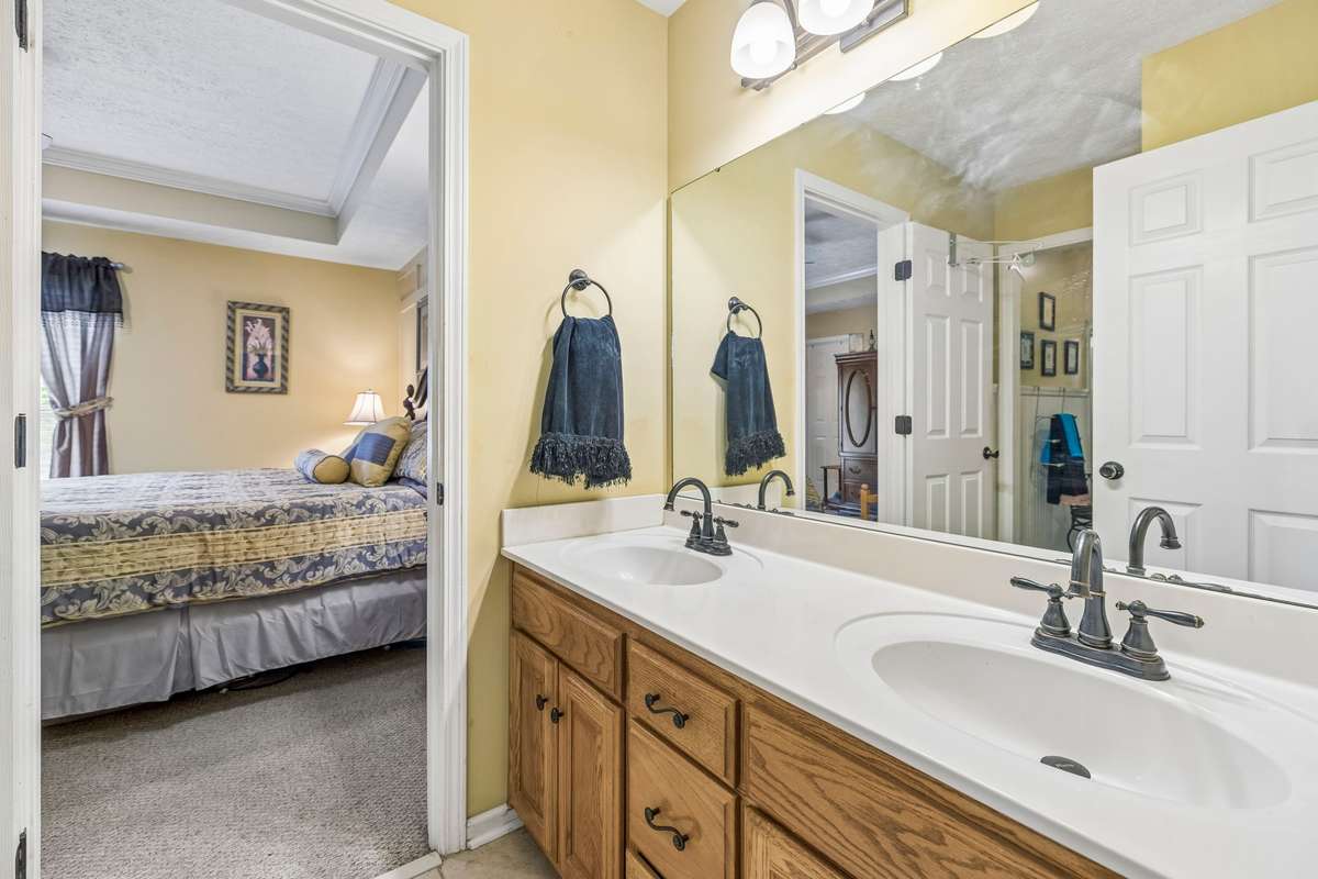 The full Bath for the Primary bedroom has a vanity with two sinks, combo tub/shower with shower door and tile flooring.