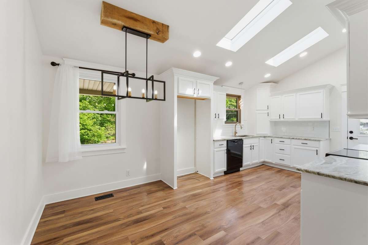 Completely remodeled kitchen with bright white cabinetry, recessed lighting, skylights, and granite countertops