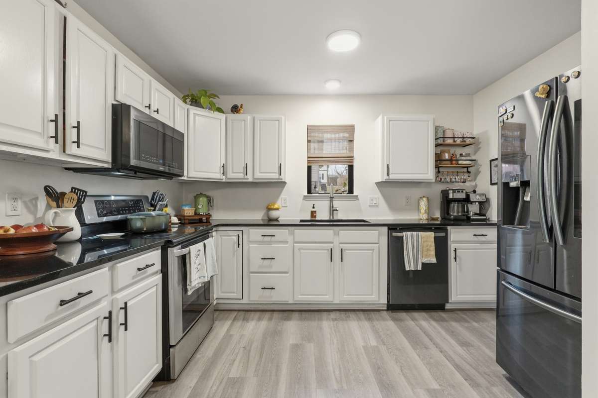 Beautiful kitchen with chrip white cabinetry, black countertops and stainless steel appliances.