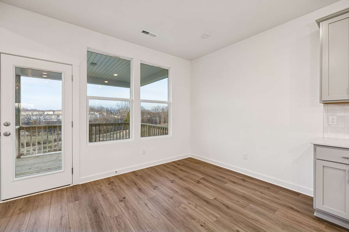Picture of model home and not of actual home being built.  Kitchen nook area that will open up to a large covered deck of rear of home overlooking trees.