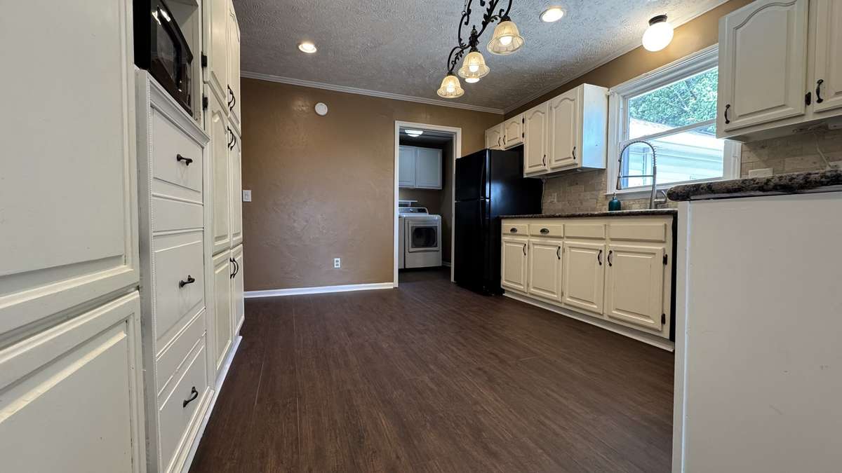 Cabinets on both sides of kitchen. Room for a table in the middle if desired. Large sink with great faucet design complete with garbage disposal.  Picture shows utility room with washer and dryer at end of kitchen