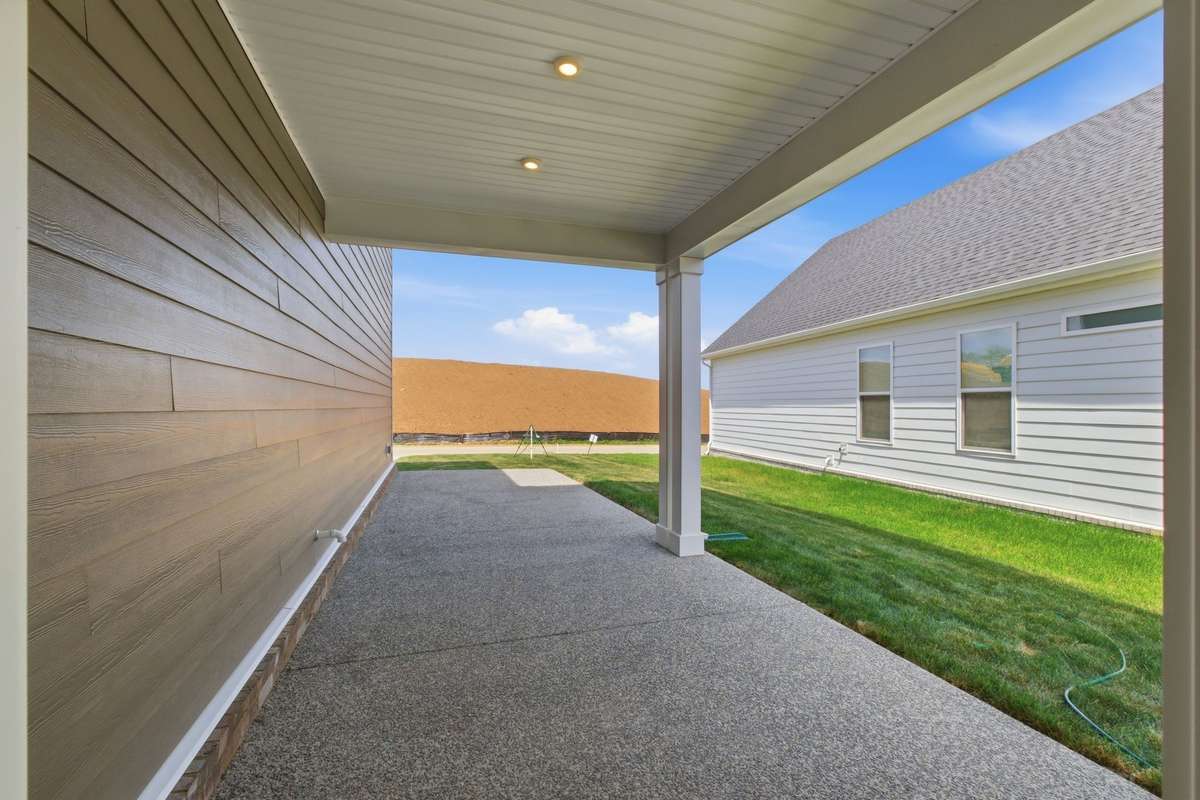 Side covered patio with extended concrete.