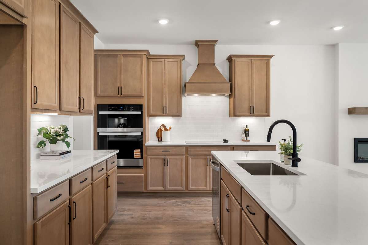 Warm stained cabinetry, wood vent hood, quartz countertops, classic subway tile backsplash and black fixtures make this kitchen a showstopper!