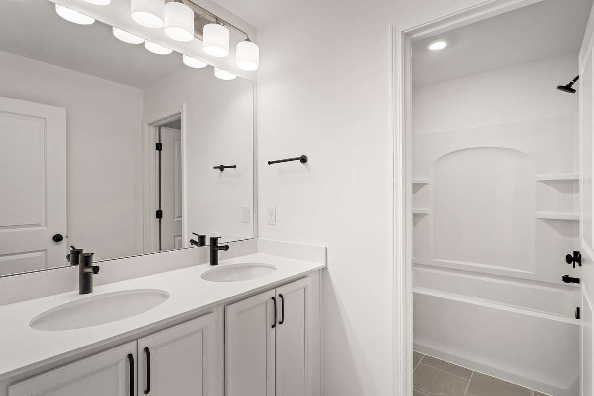 Upstairs bathroom with a white double vanity with quartz countertops and tiled floor