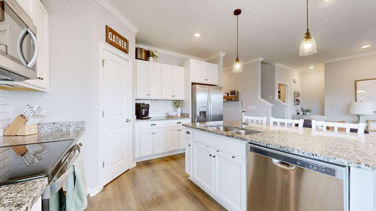 Kitchen boasts stainless steel appliances and white cabinets making the space open and bright.